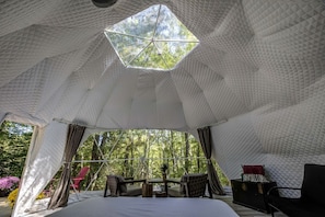 Una tenda con un soffitto geometrico, un letto, un tavolo e delle sedie.