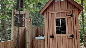 A wooden cabin with a small bathroom, a door, and a window.