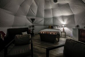 Une pièce chaleureuse, décorée de motifs géométriques, comprenant un lit, une table de chevet, une lampe et un coin salon.