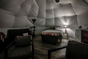 Una habitación acogedora con un diseño geométrico, una cama, mesita de noche, lámpara y zona de estar.