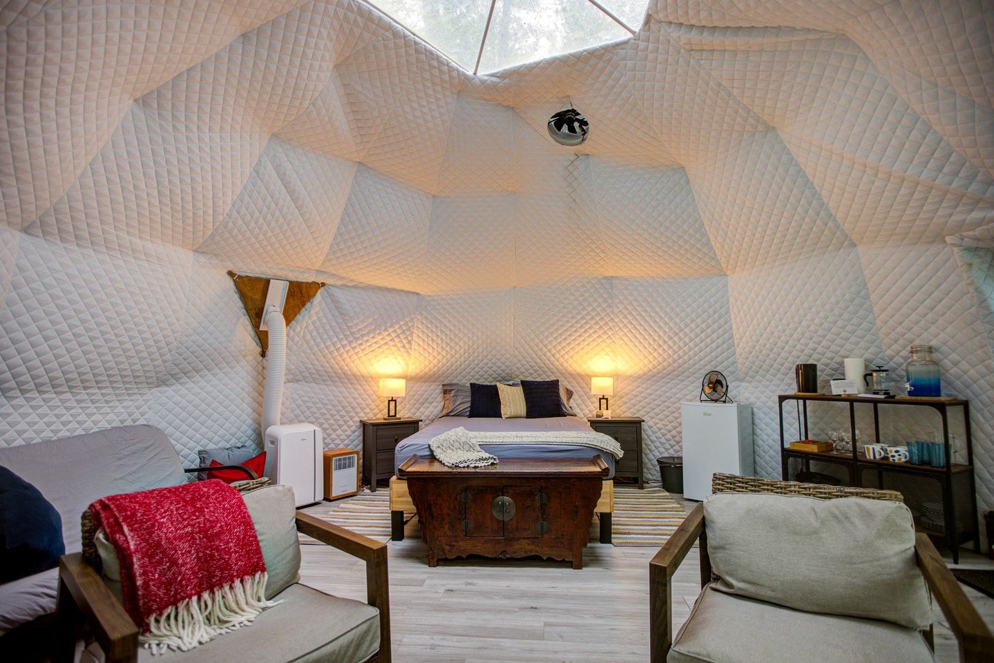 Une pièce confortable et bien éclairée, aménagée comme une tente, avec un lit, un coin salon et une petite table.