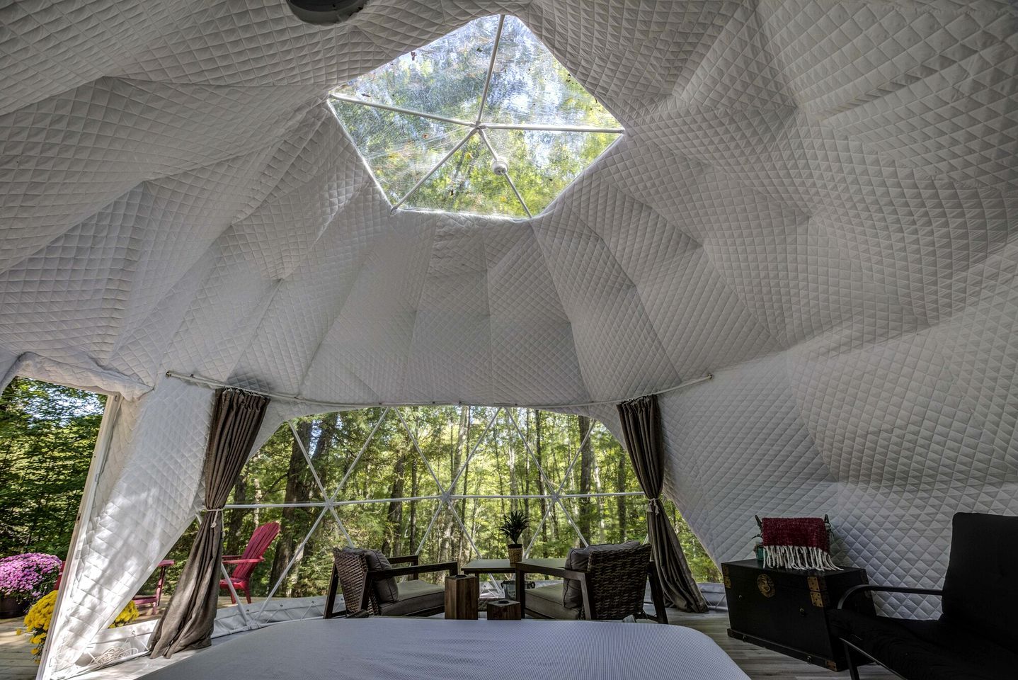 A tent with a geometric ceiling, a bed, a table, and chairs.