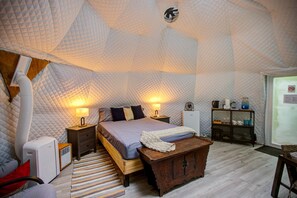 Una camera da letto con un letto, comodini, un termosifone, un radiatore, un baule di legno e una finestra.