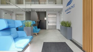 A modern lobby with a blue sofa, a staircase, and a sign for Riverfront Apartments. - Riverfront by Grand Apartments (Gdańsk)