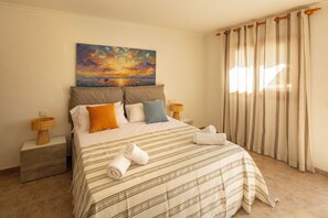 A hotel room with a bed, pillows, a painting, curtains, and a nightstand. - Can Damià _ San Josep _ Ibiza (Sant Josep de sa Talaia)