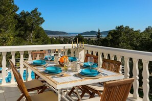 A dining table set with blue plates, glasses, and a candelabra, overlooking a scenic landscape with trees and hills. - Can Damià _ San Josep _ Ibiza (Sant Josep de sa Talaia)