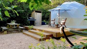 A tent with a wooden deck, outdoor seating, and a hammock.