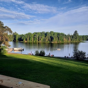 A lakeside view with a dock, chairs, and a grassy area.