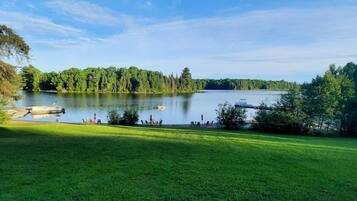 A lake with boats, a grassy area, and trees in the background.