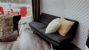 A cozy outdoor seating area with a sofa, chairs, and a rug.