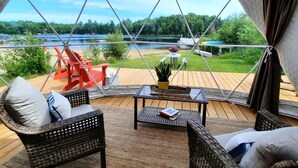 A cozy room with wicker furniture, a view of a lake, and a deck area with outdoor seating.