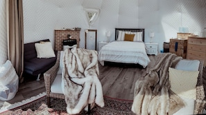 A cozy bedroom with a bed, a dresser, a nightstand, a chair, and a rug.