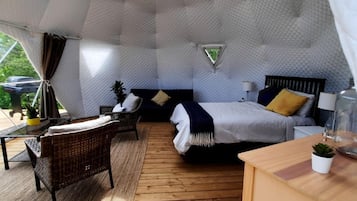 A cozy, uniquely shaped room with a bed, a small table, and a chair.