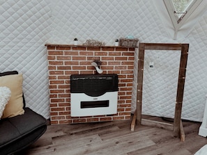 Een kamer met een schouw van baksteen, een houten frame, een witte gewatteerde wand en een houten vloer.