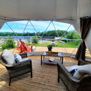 A cozy room with wicker furniture, a view of a lake, and a deck area with outdoor seating.