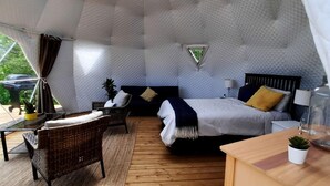 A cozy, uniquely shaped room with a bed, a small table, and a chair.