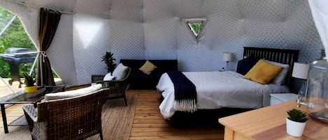 Habitació acollidora i d'una forma peculiar amb un llit, una taula petita i una cadira.