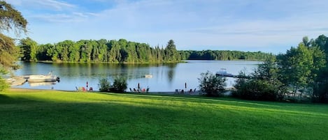 A lake with boats, a grassy area, and trees in the background.