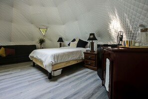 Ein Schlafzimmer mit Bett, Nachttischen, Schreibtisch und einer Zimmerpflanze.