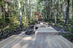 A wooden deck leading to a cabin in a forest.