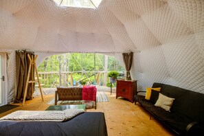 Alojamiento con carpa, suelo de madera, un sofá, una mesita y una silla.