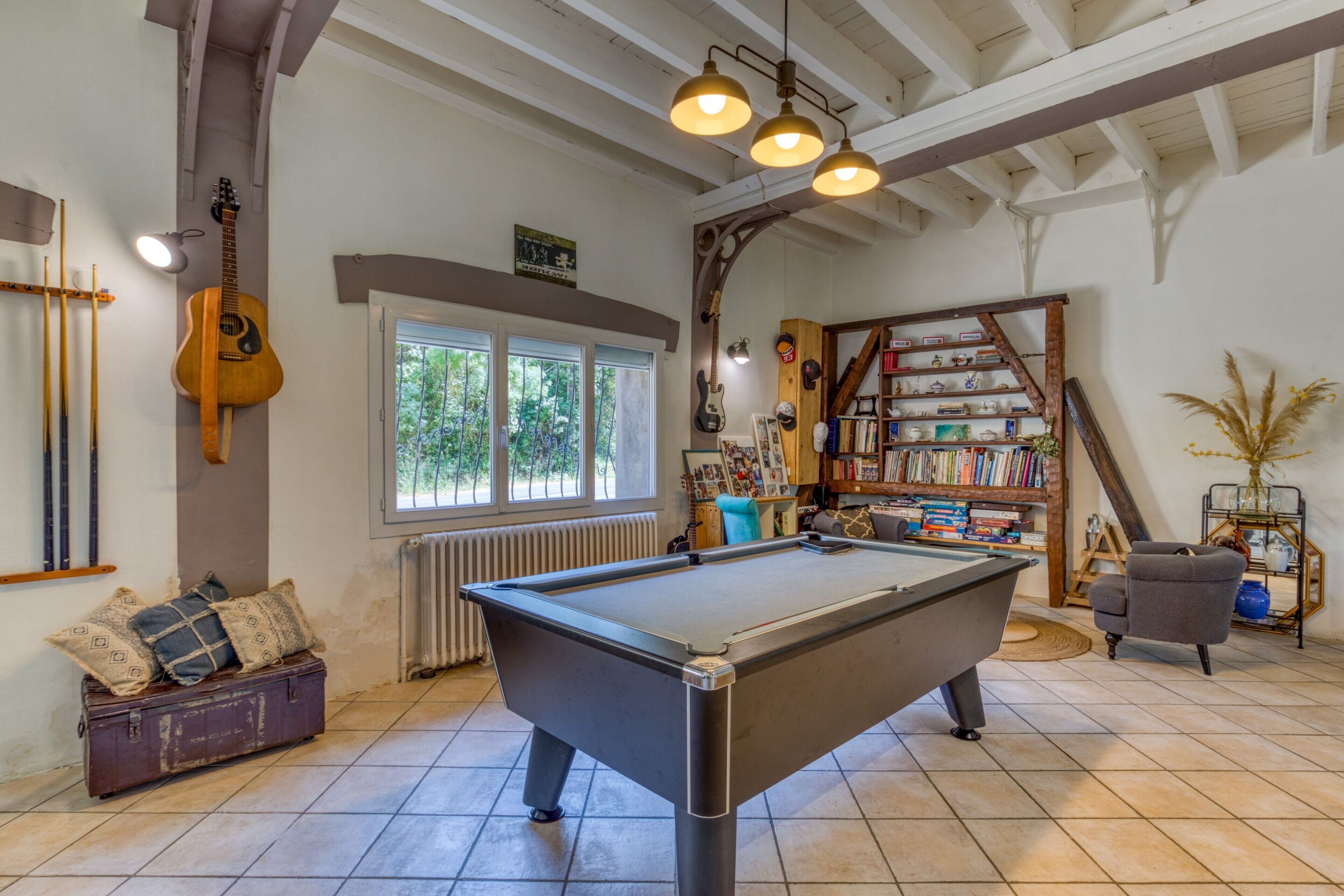 Een pooltafel in een kamer met een gitaar, boekenkasten en een radiator.