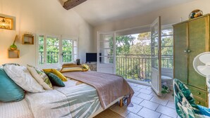 Een slaapkamer met een bed, een televisie, een balkon en een kledingkast.
