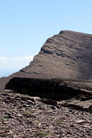 A rocky terrain with a large, steep hill in the background.