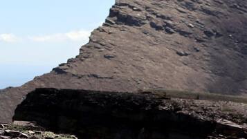 A rocky terrain with a large, steep hill in the background.