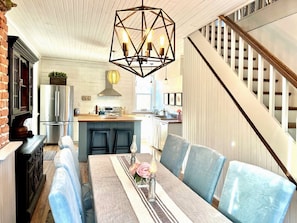 Una cocina moderna con comedor, escalera y candelabro.