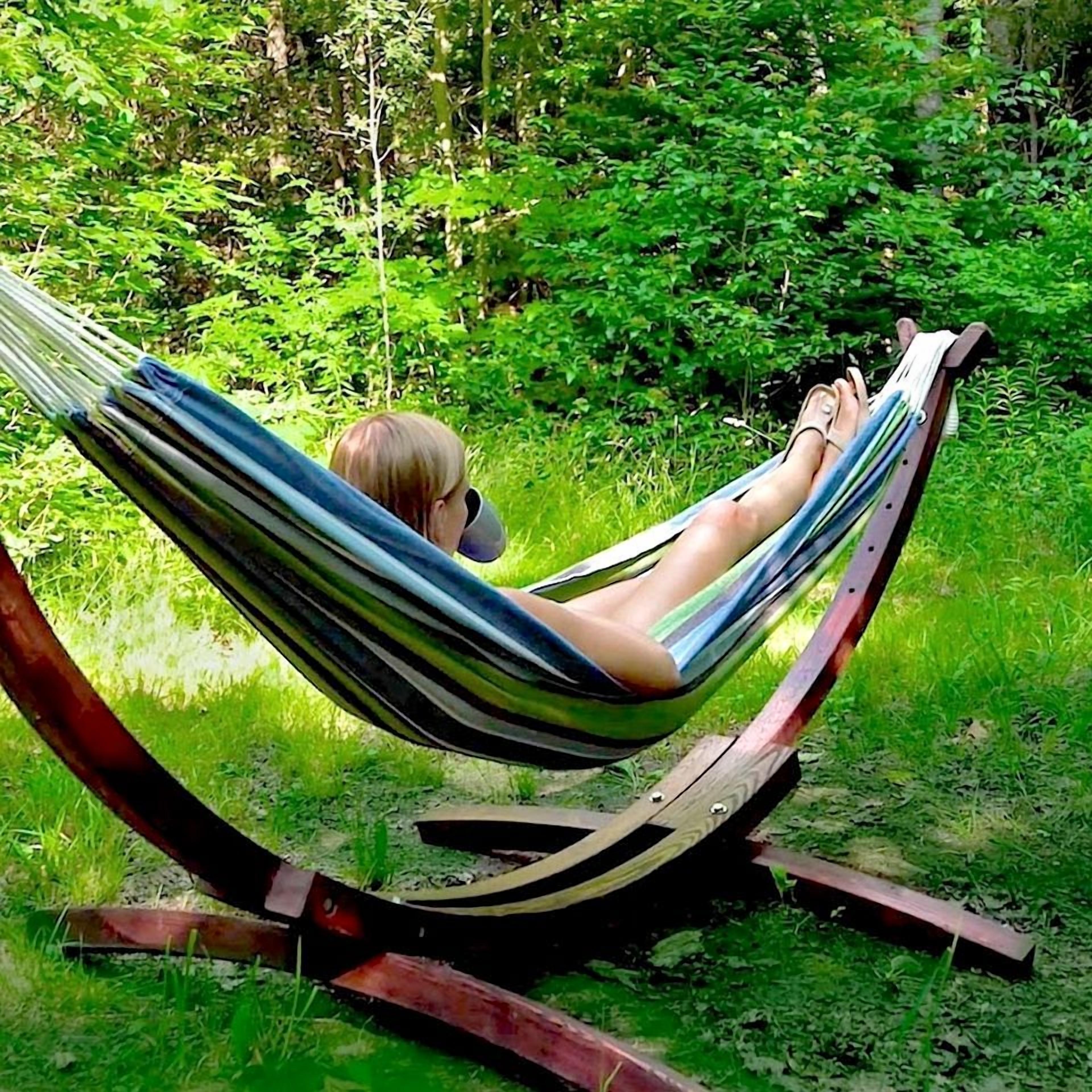A hammock in a grassy area with dense foliage in the background.