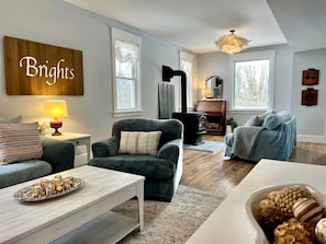 A living room with a fireplace, a sofa, a coffee table, and a sign that reads 'Brights'.