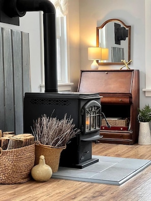A wood-burning stove, a mirror, a lamp, and a wicker basket.