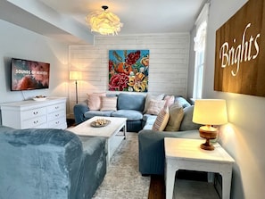 A living room with a sofa, coffee table, TV, and artwork.