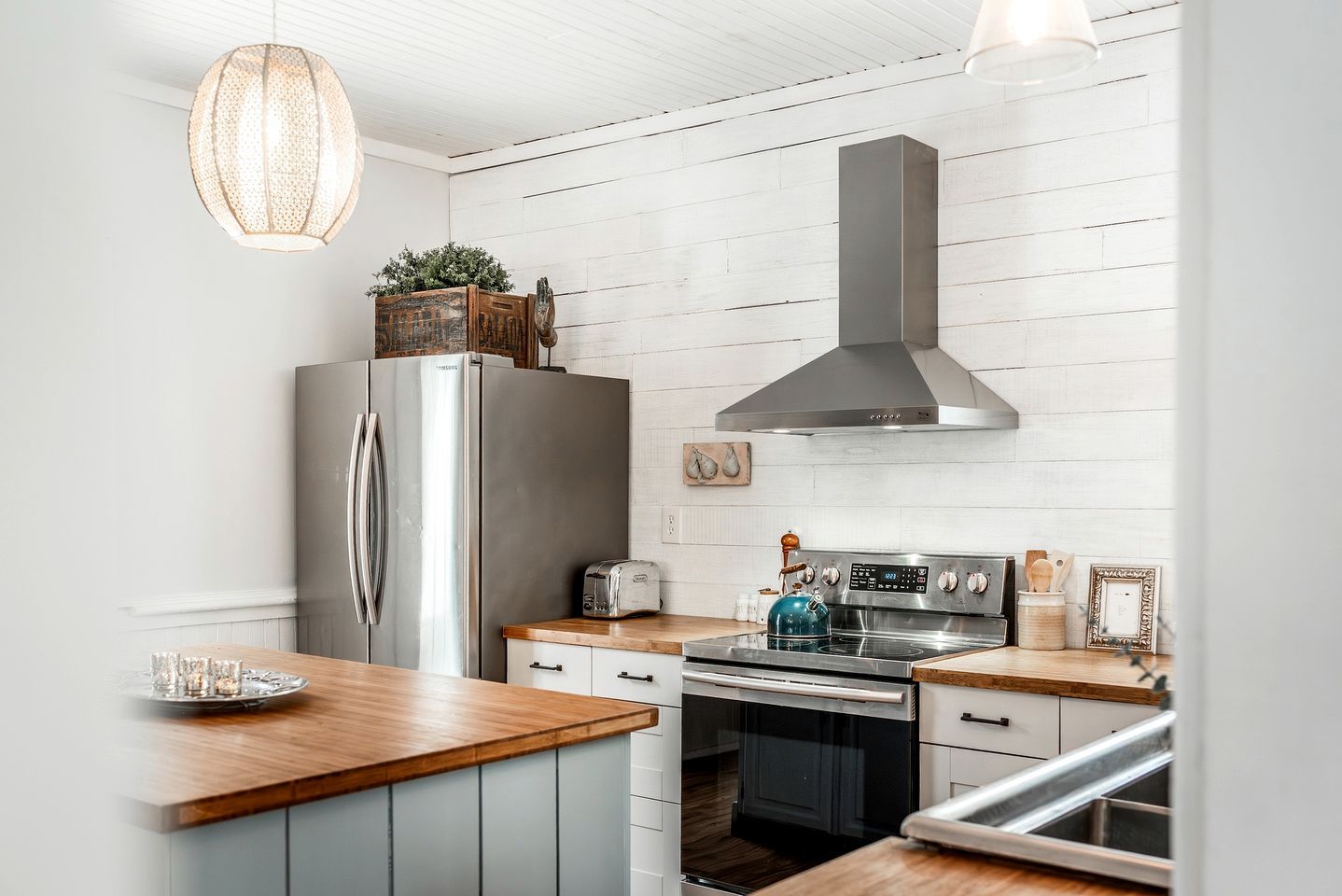 A modern kitchen with a stainless steel refrigerator, a built-in oven, a stove, and wooden countertops.