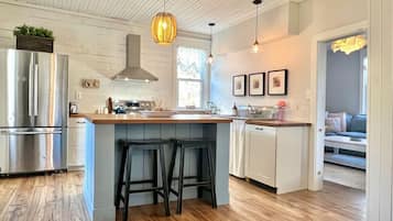 A modern kitchen with a central island, bar stools, stainless steel appliances, and pendant lighting.