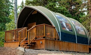 A wooden cabin with a curved roof and a wooden deck.