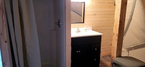 Une petite salle de bain avec un mur en bois, un lavabo blanc et un meuble noir.