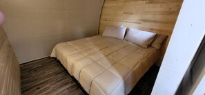 A bedroom with a wooden headboard, a quilted bedspread, and a wooden floor.