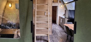 Un intérieur en bois avec un escalier, un coin cuisine et une vue par une fenêtre.