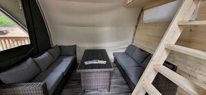 A cozy interior with a sofa set, a wicker table, and a wooden ladder.