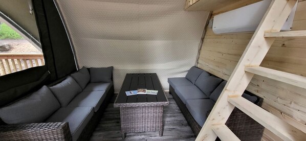 A cozy interior with a sofa set, a wicker table, and a wooden ladder.