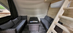 Un intérieur chaleureux avec un ensemble de canapés, une table en osier et une échelle en bois.