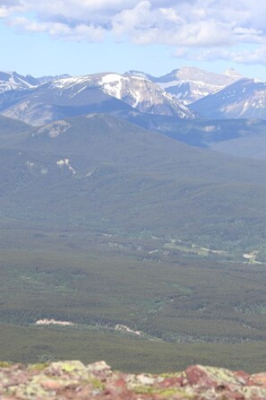 A mountainous landscape with snow-capped peaks and dense forest.