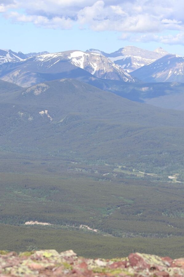 A mountainous landscape with snow-capped peaks and dense forest.