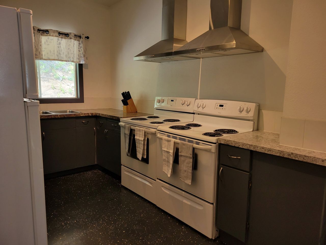 A kitchen with a stove, oven, and a window with a curtain.