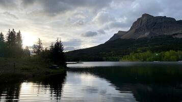 A calm lake with a mountain in the background and trees on the left.