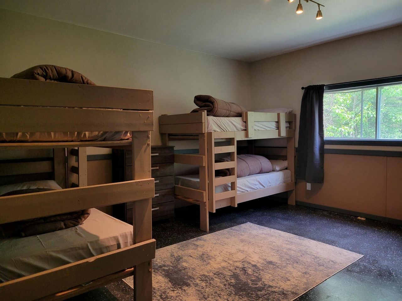 A bunk bed room with a window, a desk, and a chair.