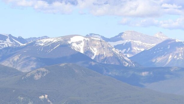 A mountainous landscape with snow-capped peaks and dense forest. - Group Cabin Lodge Surrounded by Nature with Beautiful Hiking Trails and Views in Alberta (Beaver mines)