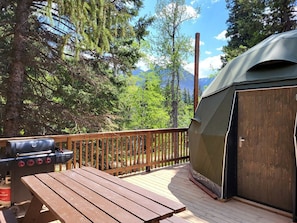 A deck with a grill, a tent, and a wooden deck railing. - Family-Friendly Dome Perfect for a Cozy and Tranquil Escape in Alberta (Beaver Mines)